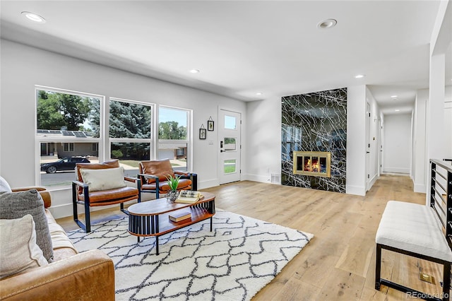 living room with a high end fireplace and light hardwood / wood-style flooring