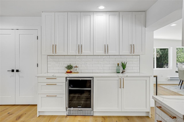 bar with light stone countertops, beverage cooler, backsplash, and white cabinetry