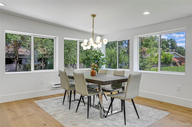 dining space featuring baseboard heating, light wood-type flooring, and an inviting chandelier