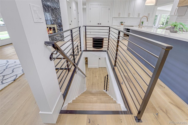 staircase with sink, a fireplace, and hardwood / wood-style flooring