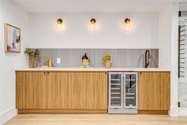 bar featuring sink, light wood-type flooring, and wine cooler