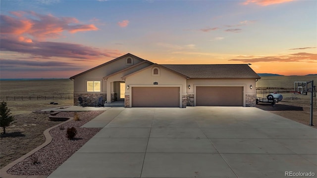 single story home with an attached garage, fence, stone siding, driveway, and stucco siding