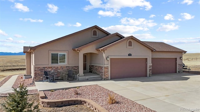 ranch-style home with an attached garage, stone siding, concrete driveway, and stucco siding