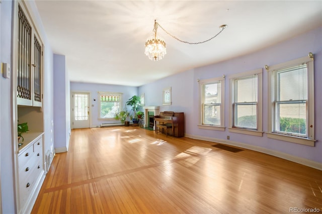 interior space featuring a baseboard heating unit, light wood-type flooring, and an inviting chandelier