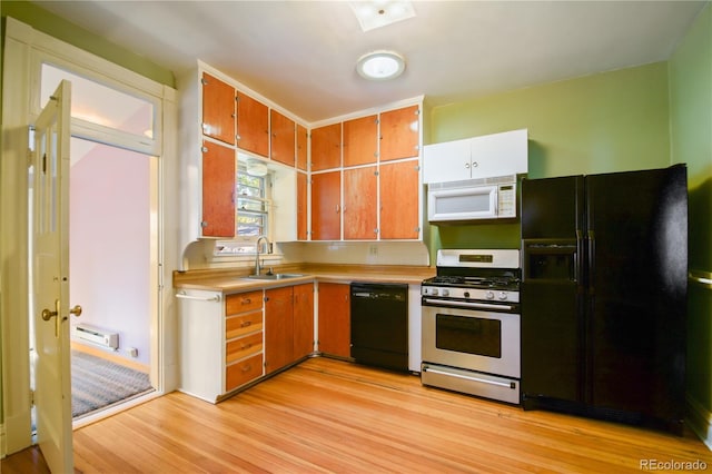 kitchen with sink, light hardwood / wood-style floors, a baseboard radiator, and black appliances