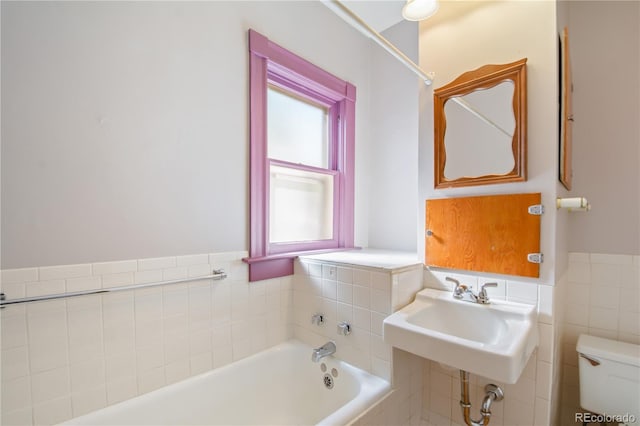 bathroom with toilet, a tub, and sink