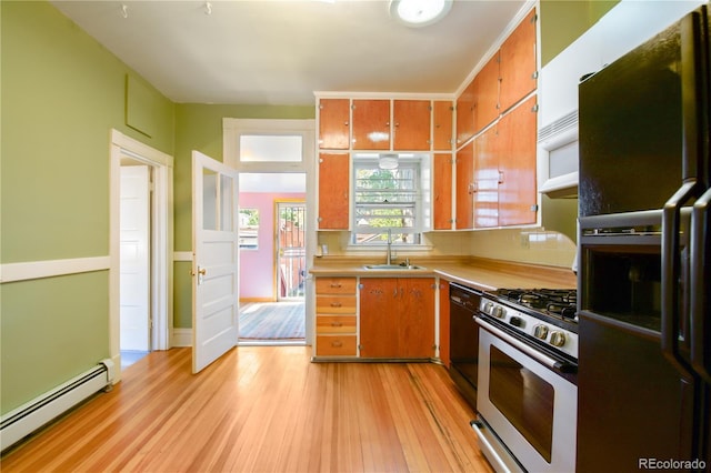 kitchen with dishwasher, stainless steel gas range, refrigerator with ice dispenser, a baseboard heating unit, and sink