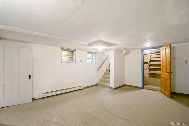 basement featuring a textured ceiling, a baseboard heating unit, and light carpet