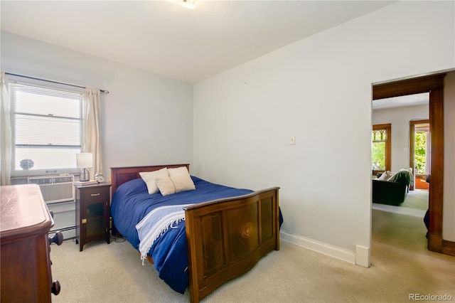 bedroom featuring light carpet, cooling unit, multiple windows, and a baseboard radiator