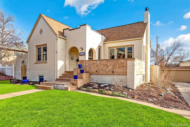 view of front of home with a chimney, stucco siding, a shingled roof, fence, and a front lawn