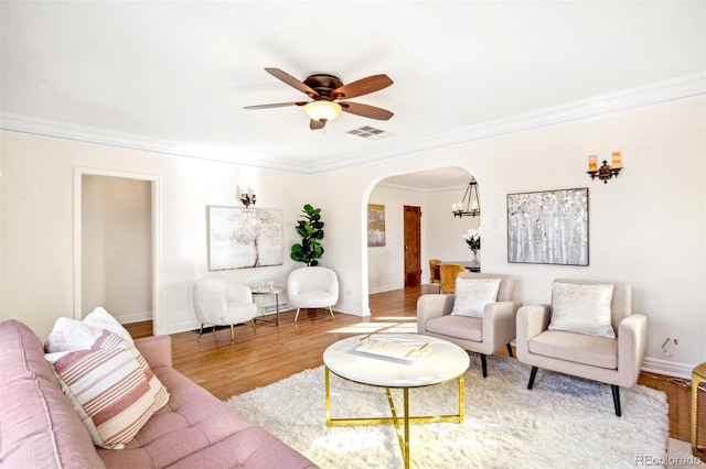 living area with arched walkways, ceiling fan, wood finished floors, visible vents, and baseboards