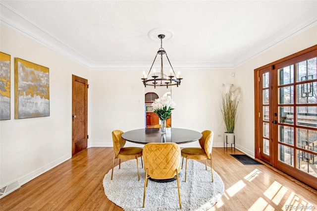 dining room with ornamental molding, light wood-style floors, visible vents, and a notable chandelier