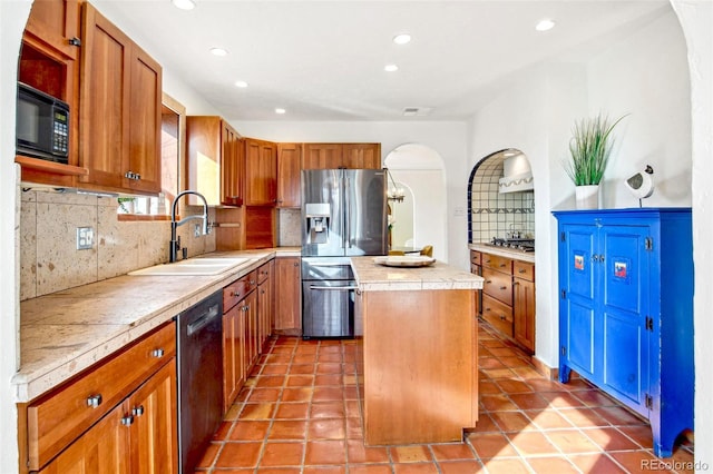 kitchen with a sink, a kitchen island, decorative backsplash, brown cabinets, and black appliances