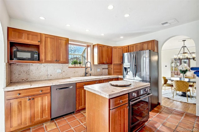 kitchen with visible vents, a kitchen island, a sink, black appliances, and backsplash