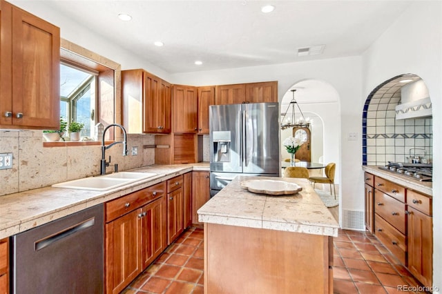 kitchen with visible vents, a kitchen island, appliances with stainless steel finishes, light countertops, and a sink