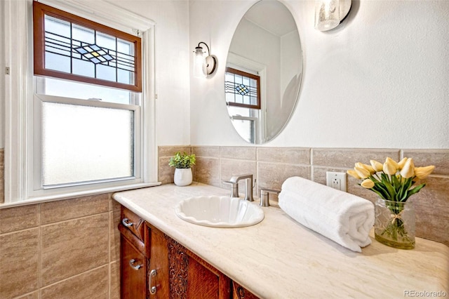 bathroom with a healthy amount of sunlight, tile walls, and vanity