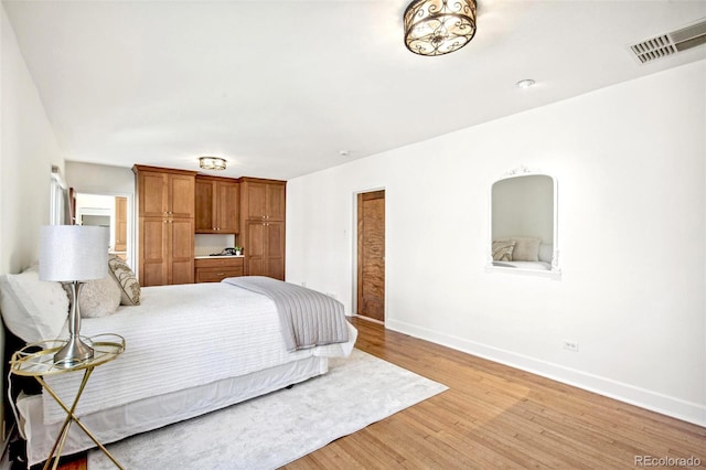 bedroom with light wood finished floors, visible vents, and baseboards