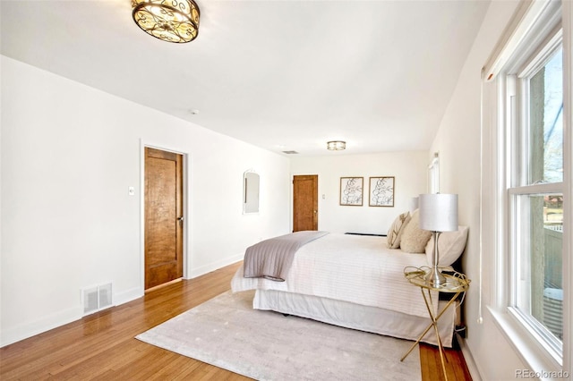 bedroom featuring baseboards, visible vents, and wood finished floors