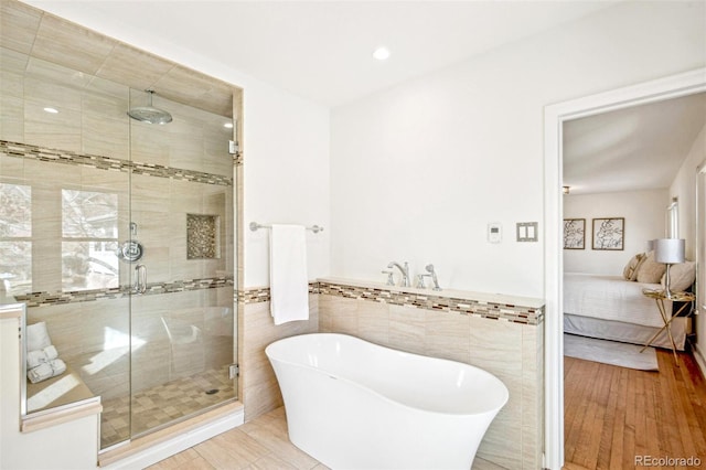 full bath featuring a stall shower, wainscoting, tile walls, and ensuite bathroom