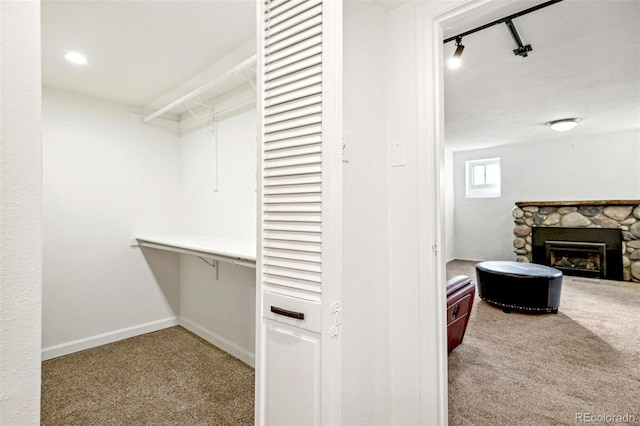 walk in closet with light carpet and a fireplace