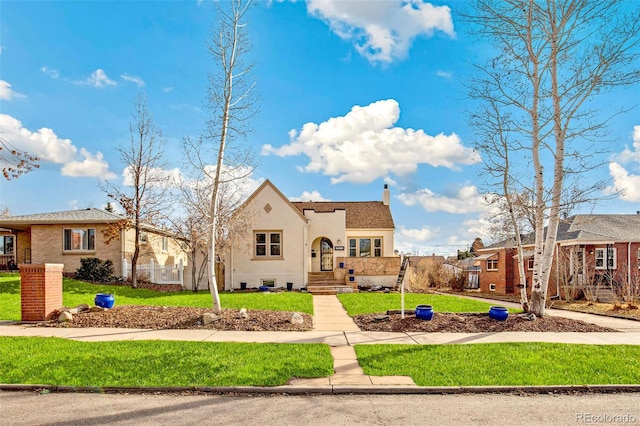 view of front of home featuring stucco siding, a residential view, a chimney, and a front yard