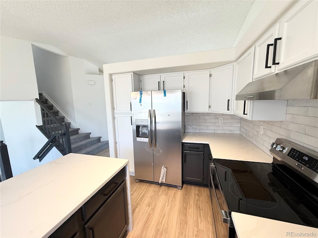 kitchen featuring light wood-style flooring, a textured ceiling, appliances with stainless steel finishes, under cabinet range hood, and light countertops