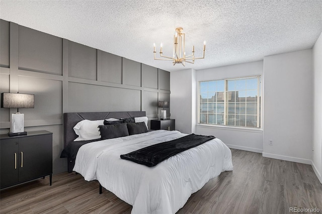 5068 E Crestone Ave, Castle Rock, CO 80104 - bedroom featuring a chandelier, wood finished floors, a textured ceiling, a decorative wall, and baseboards