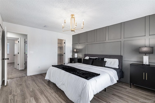 5068 E Crestone Ave, Castle Rock, CO 80104 - bedroom featuring a decorative wall, a chandelier, wood finished floors, a textured ceiling, and a spacious closet