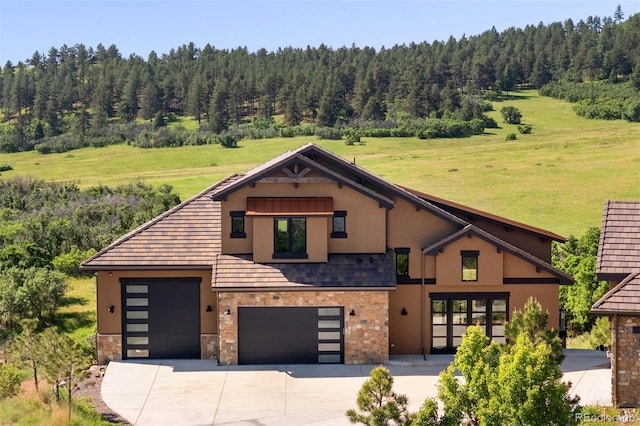 2480 Castle Butte Dr, Castle Rock, CO 80109 - view of front of home featuring stucco siding, stone siding, a wooded view, and concrete driveway