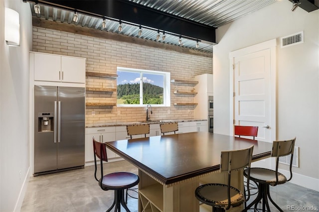 2480 Castle Butte Dr, Castle Rock, CO 80109 - kitchen with visible vents, open shelves, white cabinetry, concrete floors, and stainless steel fridge with ice dispenser