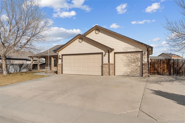 view of front of house featuring concrete driveway, brick siding, an attached garage, and fence