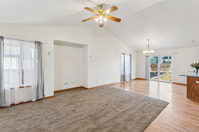 unfurnished living room featuring light wood finished floors, baseboards, vaulted ceiling, and ceiling fan with notable chandelier