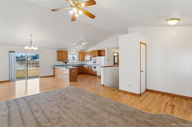 kitchen with a peninsula, white appliances, vaulted ceiling, light wood finished floors, and brown cabinetry