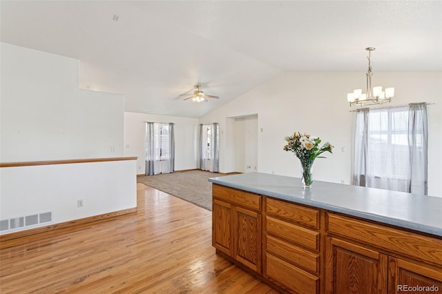 kitchen featuring light wood-style flooring, visible vents, vaulted ceiling, hanging light fixtures, and brown cabinets