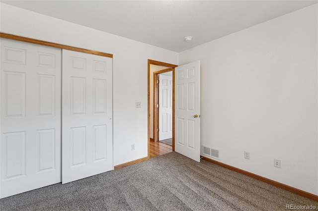 unfurnished bedroom featuring carpet floors, a closet, visible vents, and baseboards