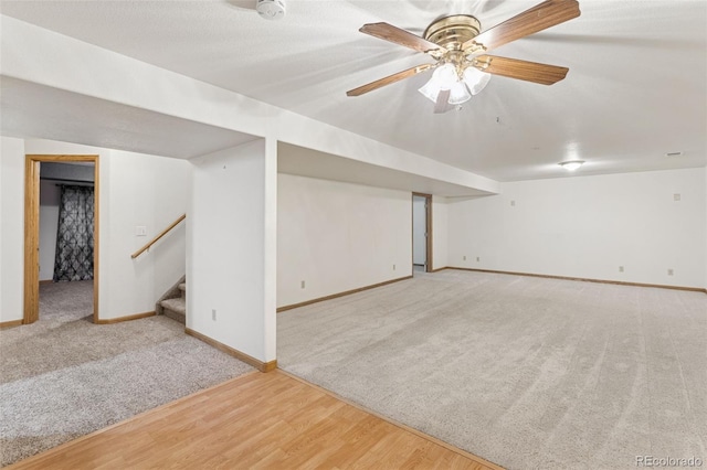 finished basement featuring carpet floors, ceiling fan, wood finished floors, baseboards, and stairs