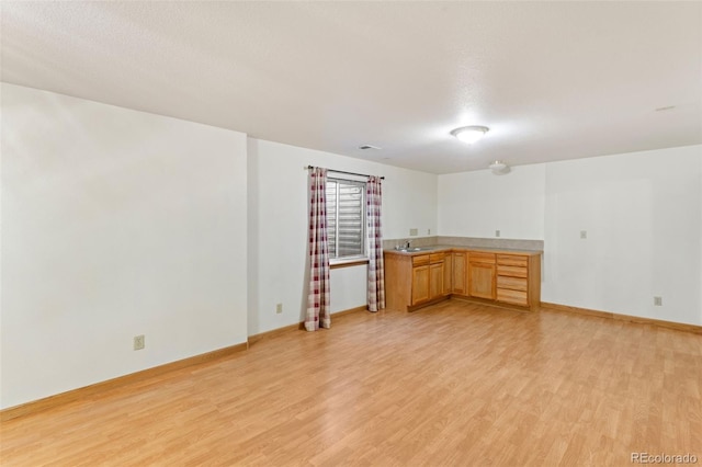 interior space featuring light wood-style floors, baseboards, and a sink