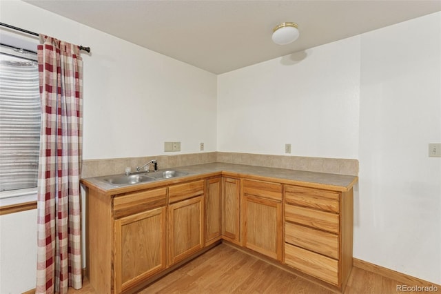 kitchen with light wood finished floors, light countertops, and a sink