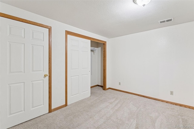 unfurnished bedroom featuring carpet, visible vents, a textured ceiling, and baseboards