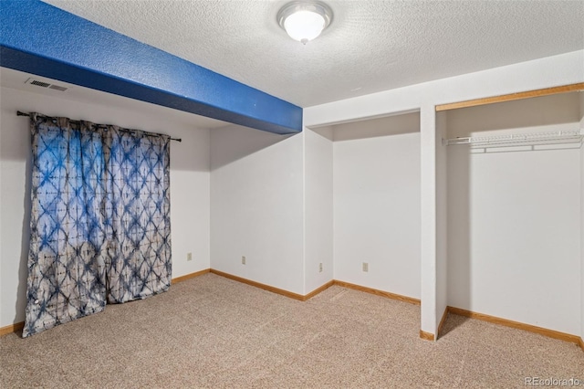 unfurnished bedroom with baseboards, a textured ceiling, visible vents, and carpet flooring