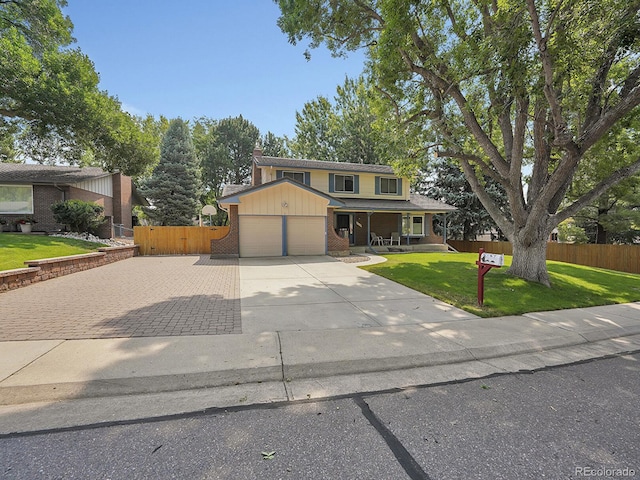 traditional-style home featuring a garage, a front yard, brick siding, and fence