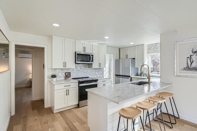 kitchen featuring a sink, a kitchen breakfast bar, tasteful backsplash, a wall unit AC, and stainless steel appliances