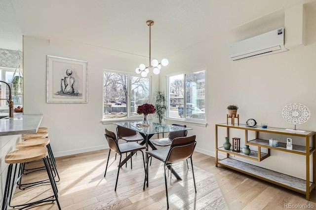 dining area with plenty of natural light, baseboards, light wood-type flooring, and a wall mounted air conditioner