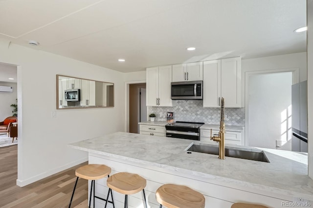 kitchen featuring a breakfast bar, light stone counters, a sink, tasteful backsplash, and stainless steel appliances