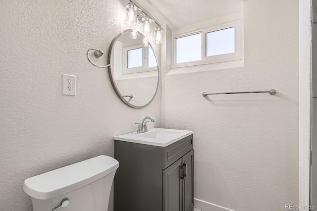 bathroom featuring vanity, toilet, and a textured wall