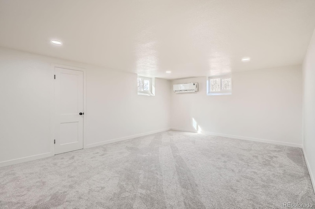 basement with a healthy amount of sunlight, carpet, and a wall mounted AC