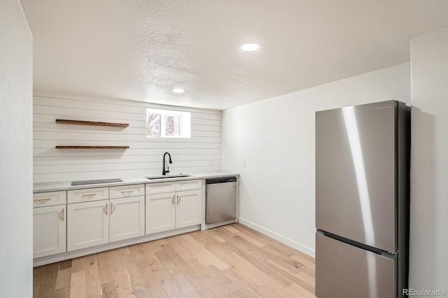 kitchen with a sink, light wood-type flooring, light countertops, stainless steel appliances, and open shelves