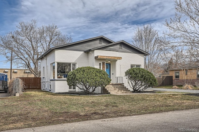 bungalow-style home with a front lawn and fence