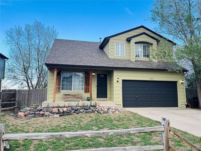 traditional home with an attached garage, roof with shingles, fence, and driveway