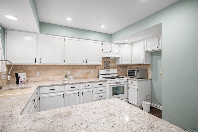 13118 Ash St, Thornton, CO 80241 - kitchen with white gas range, stainless steel microwave, white cabinets, decorative backsplash, and under cabinet range hood